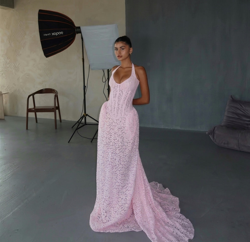 Woman in a pink lace dress standing in a studio with photography equipment.