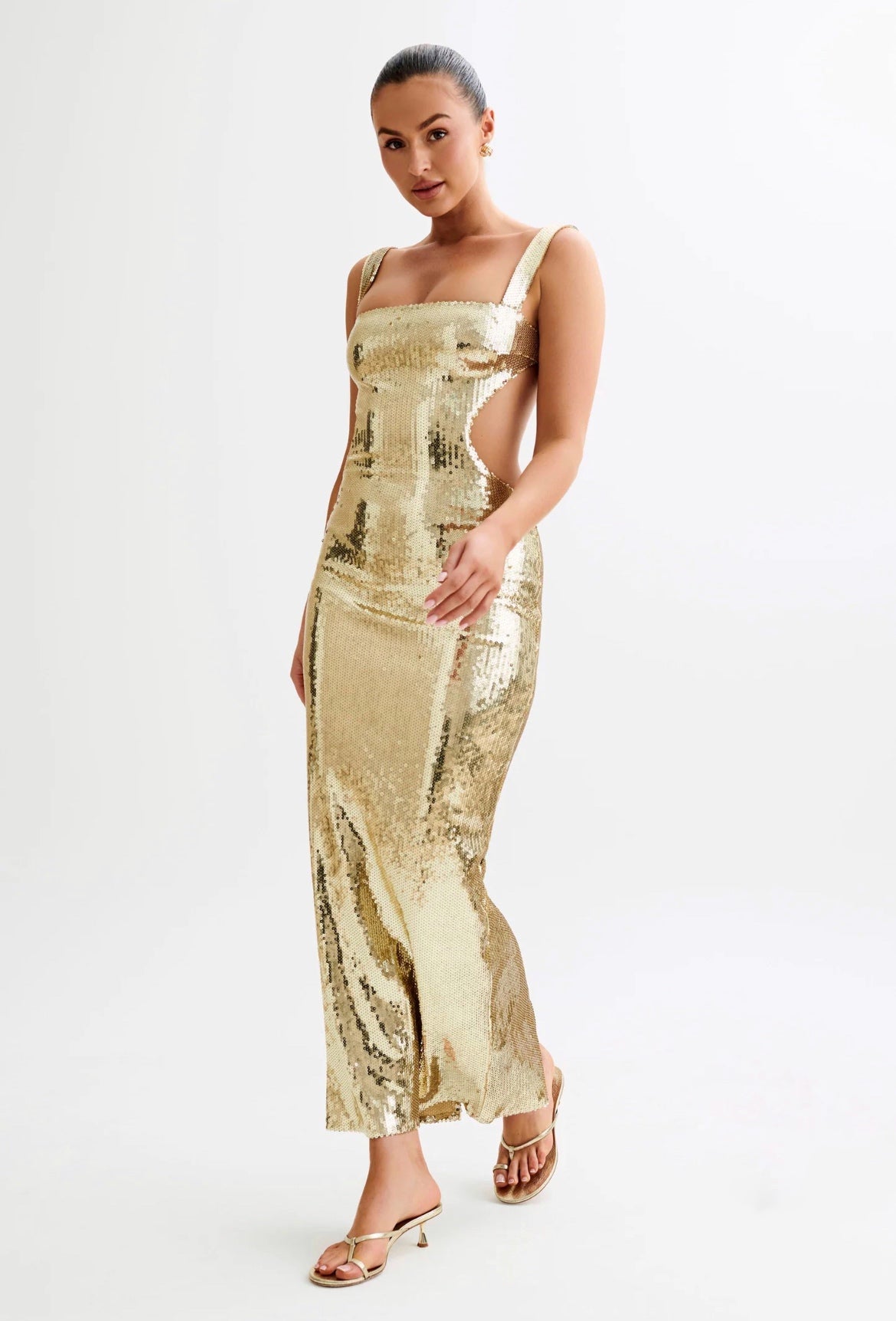 Woman wearing a gold sequin dress on a white background