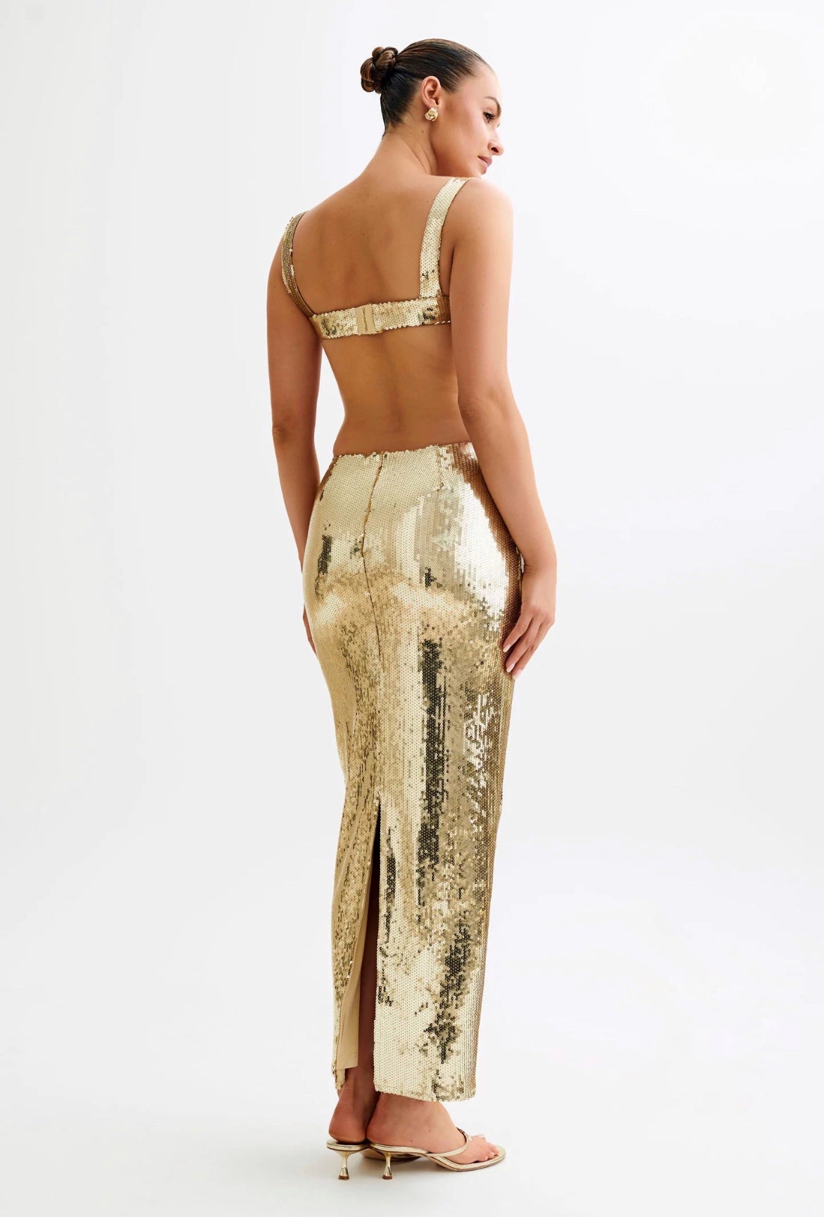 Woman wearing a gold sequin jumpsuit on a white background