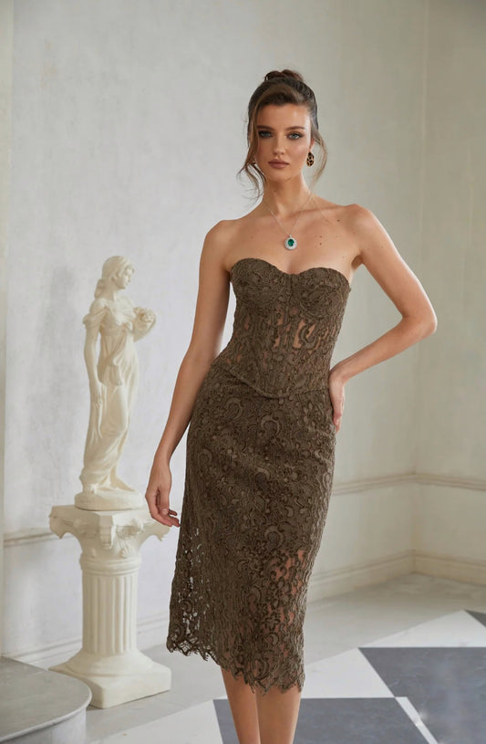 Woman wearing a strapless lace dress in an elegant room with classical sculpture.