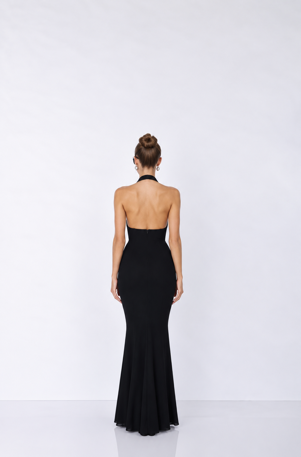 sleeveless black halter-neck gown with a deep plunging neckline, a peplum waist.