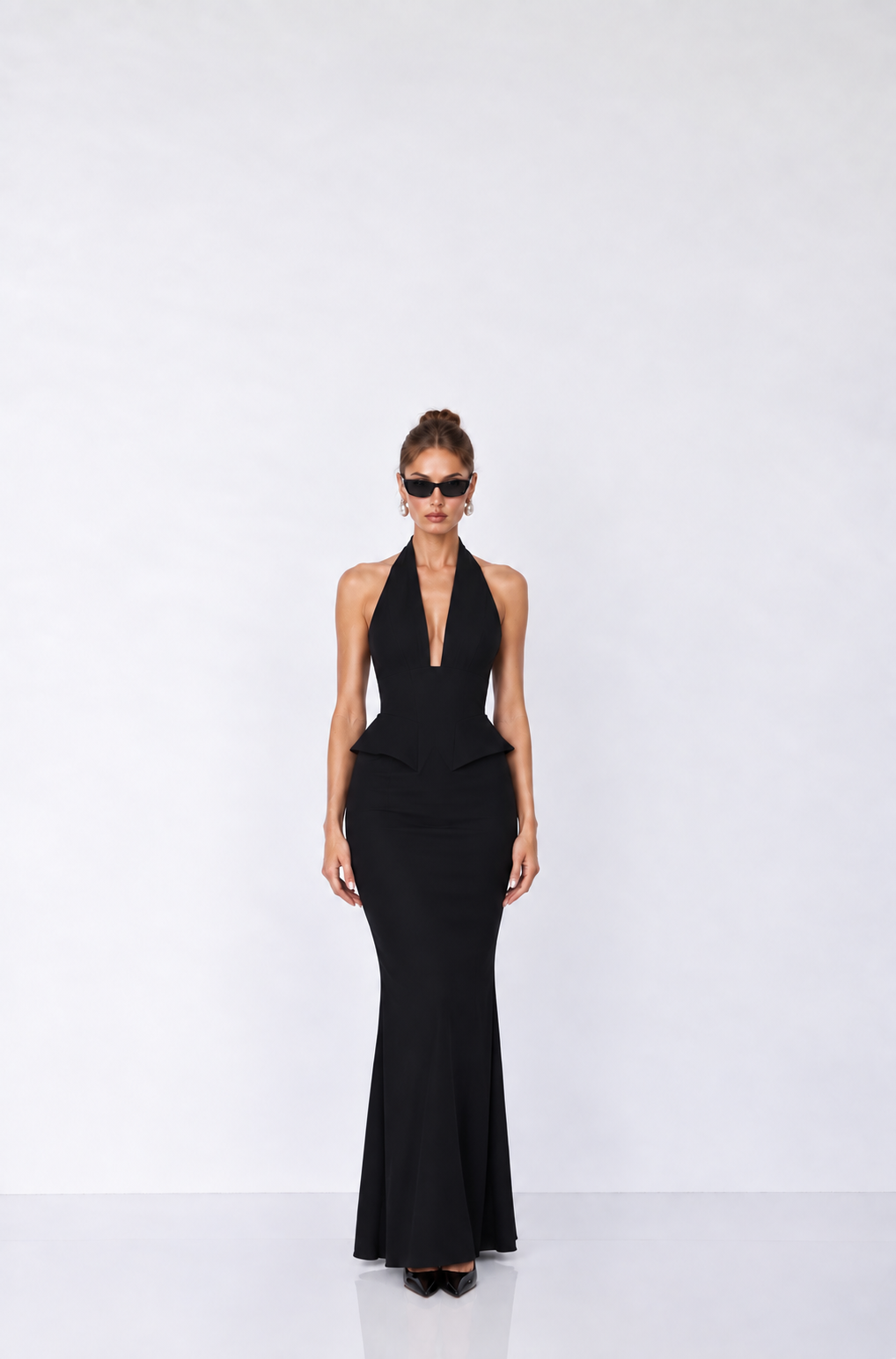 sleeveless black halter-neck gown with a deep plunging neckline, a peplum waist