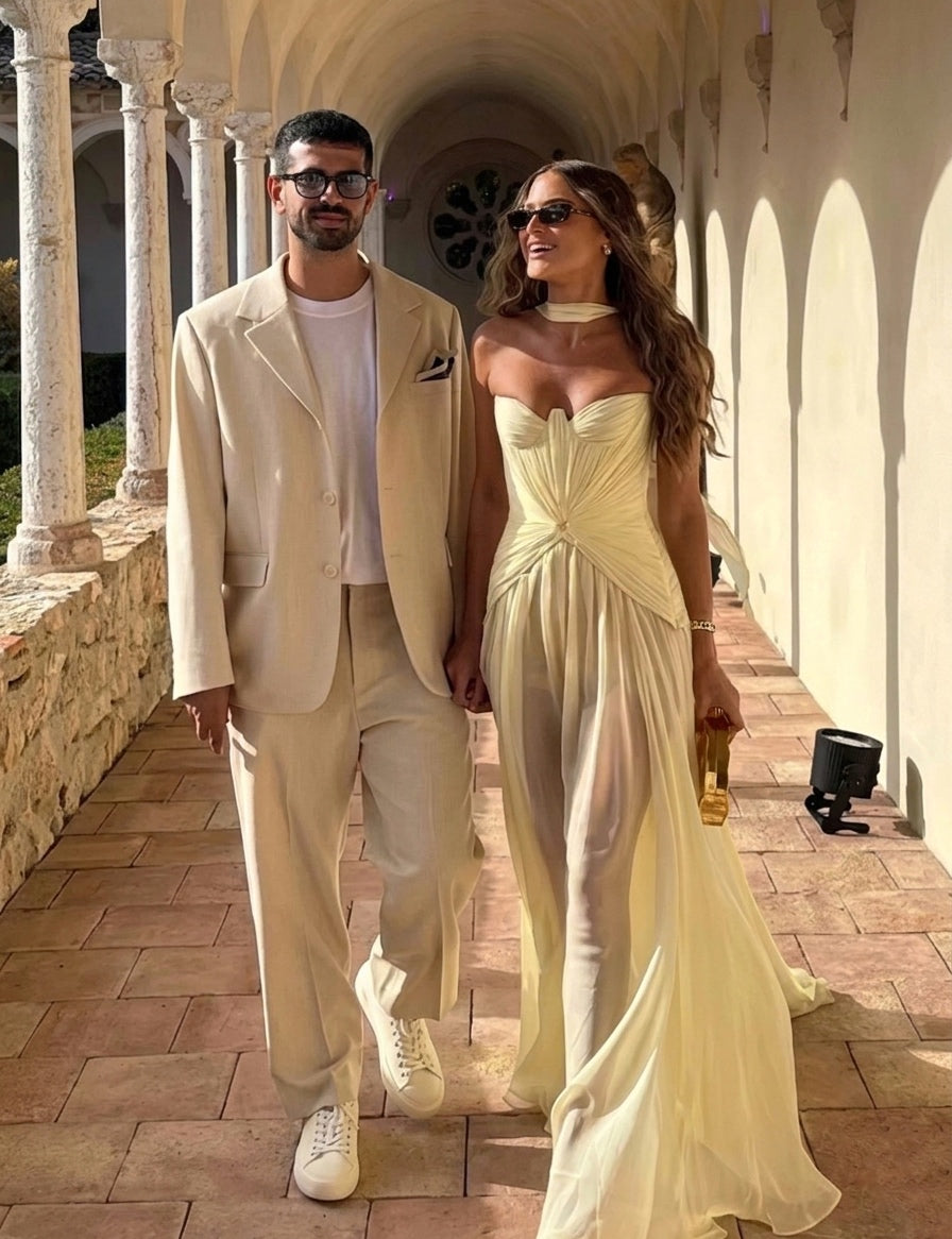 Man and woman in matching light-colored outfits walking together in an architectural setting.