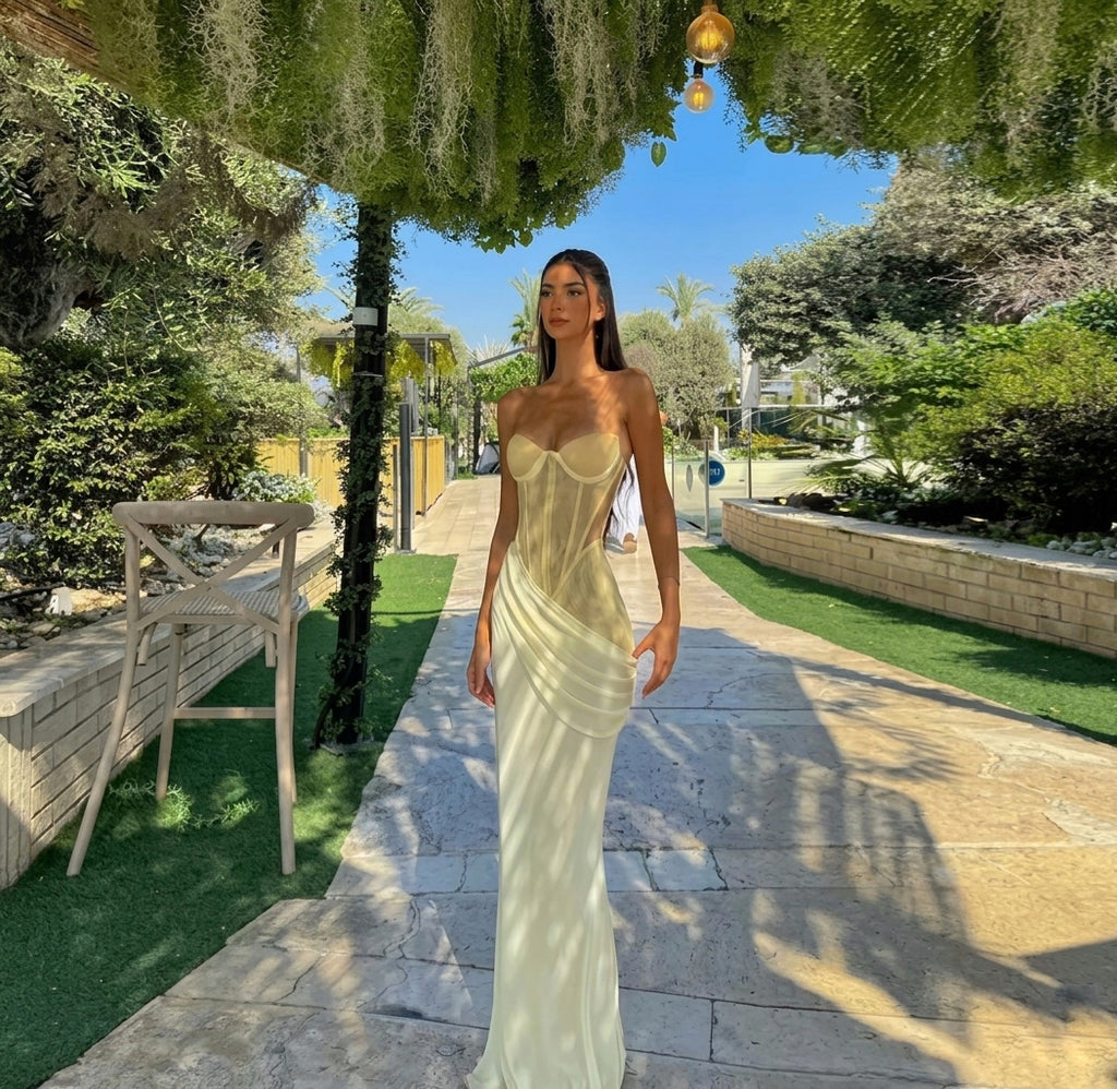 Woman in a strapless dress standing on a stone path with greenery around