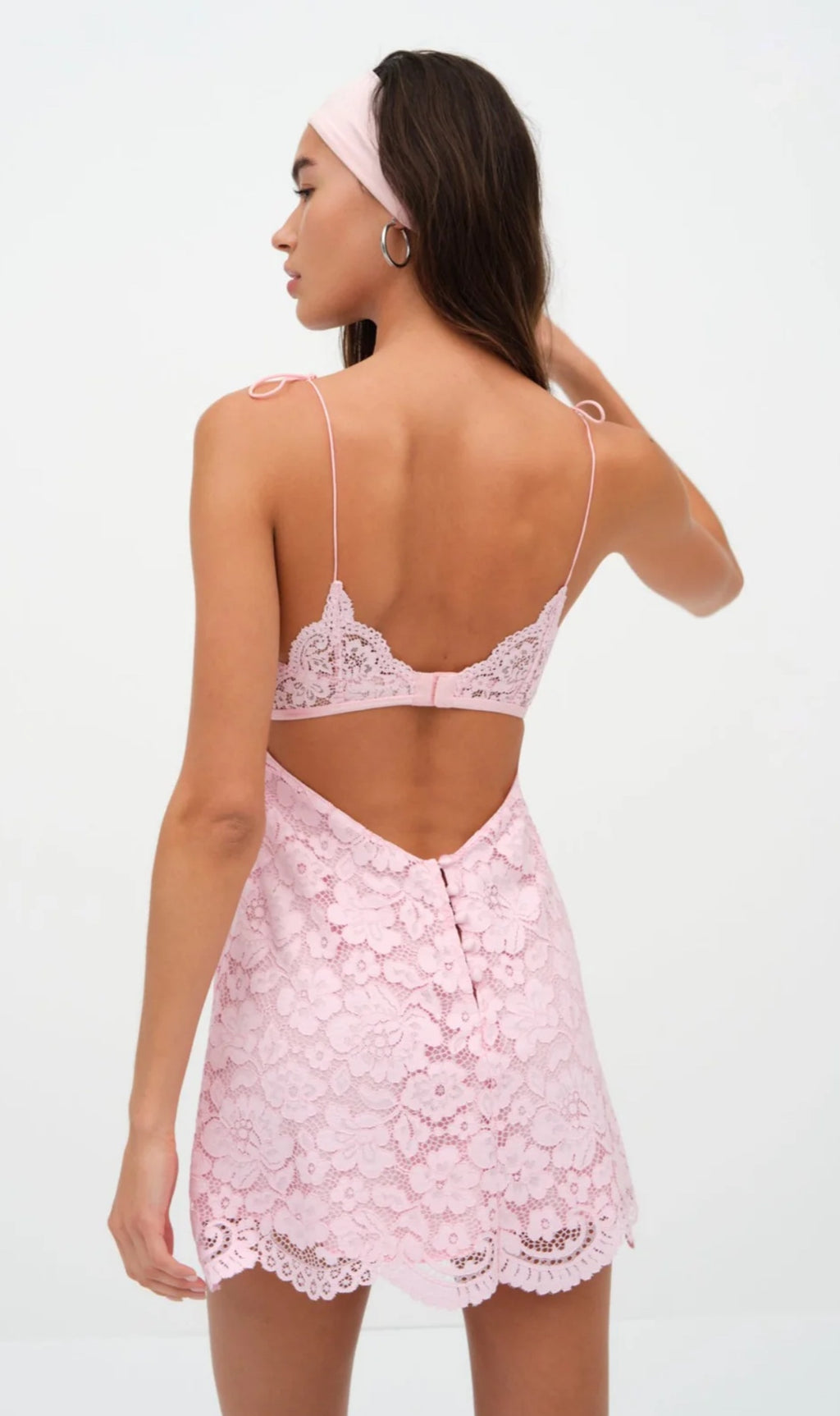 Woman wearing a pink lace nightgown with a white background