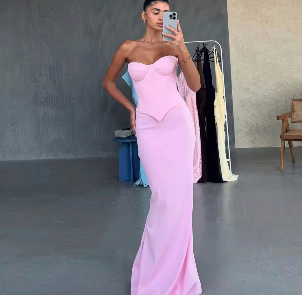 Woman in a pink strapless gown taking a mirror selfie in a room with gray walls and a chair.