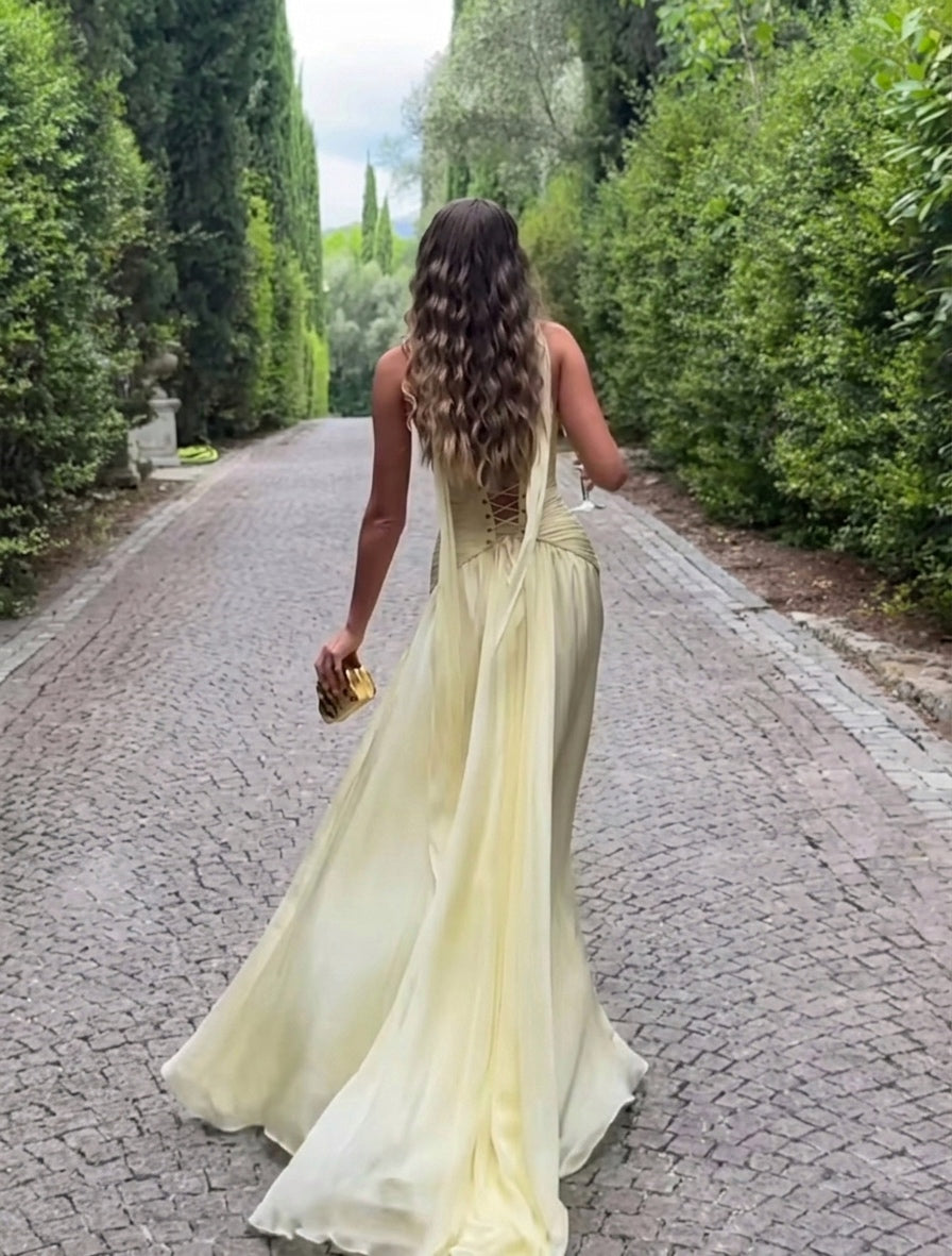 Woman in a light yellow dress walking down a tree-lined path